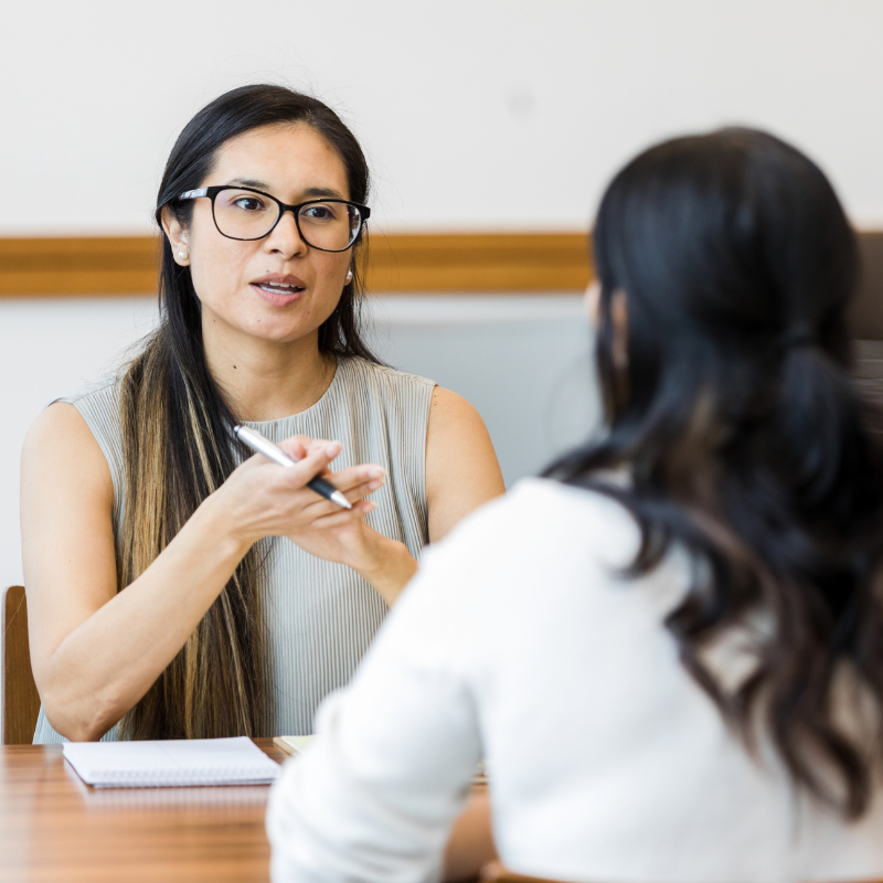 Two women sit at a table, discussing the results of an assessment.